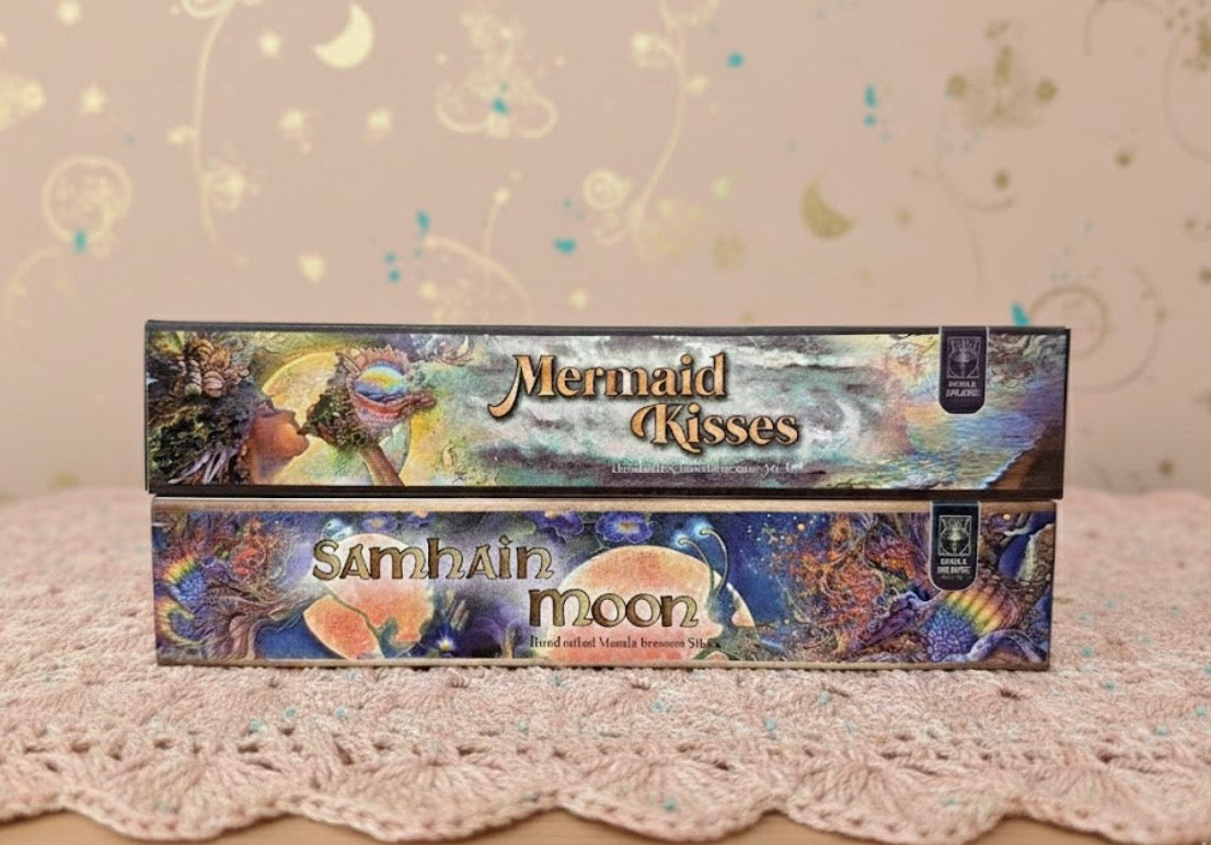 Two boxes of 'Mermaid Kisses' and 'Samhain Moon' products on a textured surface with a decorative background.
