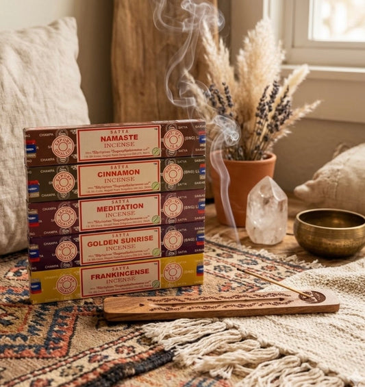 Box of Satya incense sticks with a smoking stick on a table with decorative items.