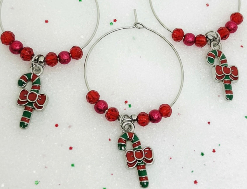 Decorative silver wine glass charm with candy cane charm on a white background.