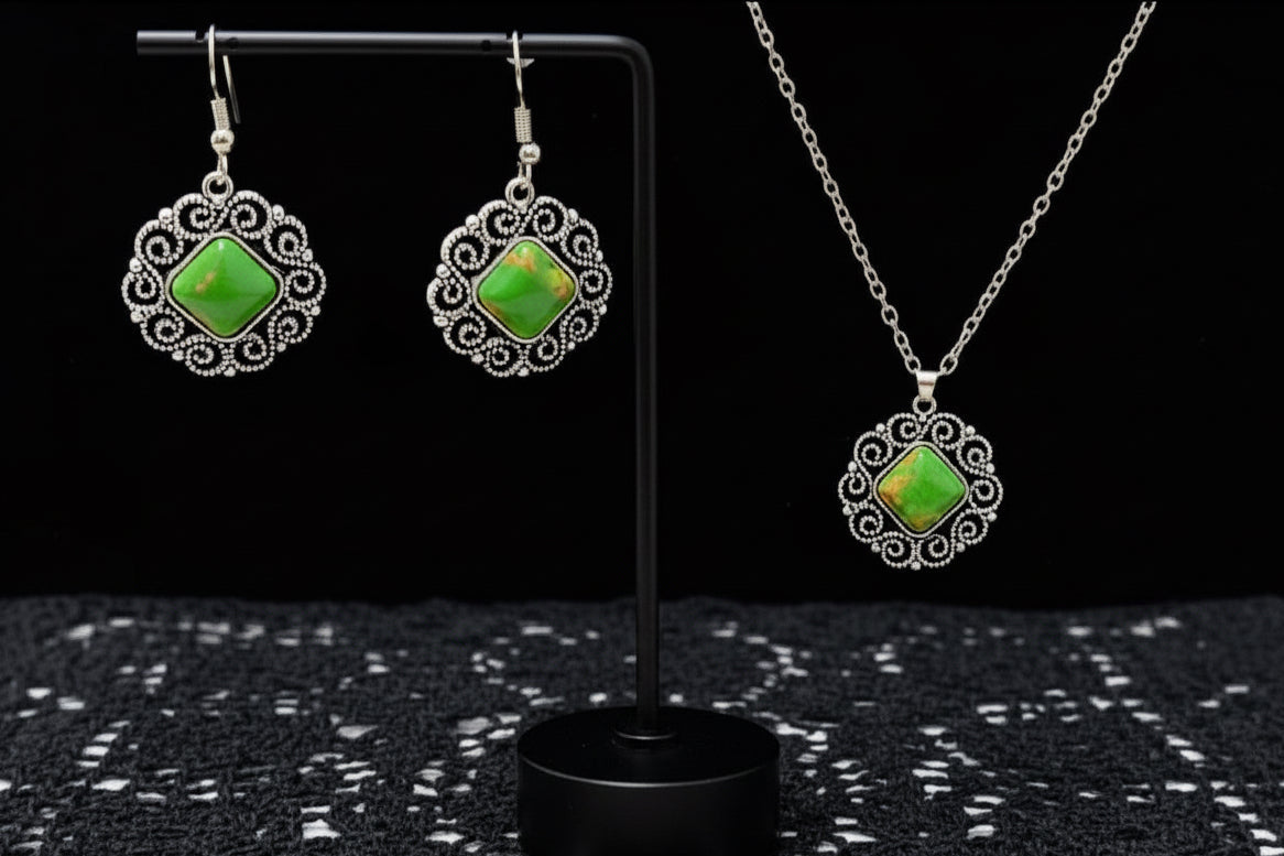 Jewelry set with green gemstones on a black stand