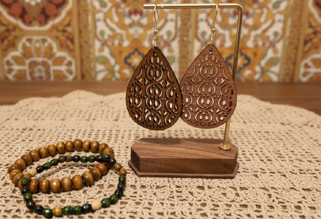 Wooden earrings on a stand with a bracelet on a textured surface