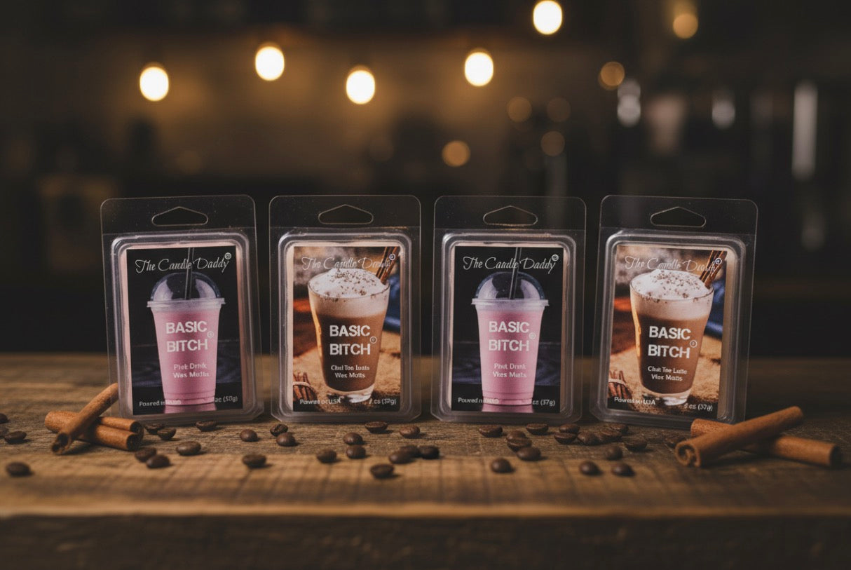 Four wax melts labeled 'Basic Bitch' on a wooden surface with cinnamon sticks and coffee beans, blurred lights in the background.