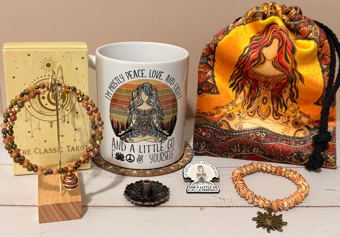 Collection of items including a mug, tarot cards, bracelet, and decorative bag on a wooden surface.