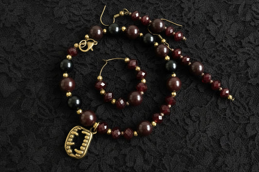 Beaded bracelet and earrings with a fangs charm on a black background