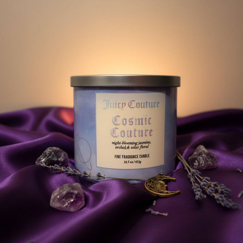 Luxury three wick candle with a purple tablecloth, flowers, and charms