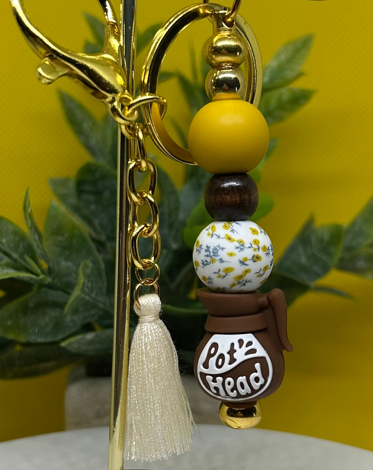 Pot head Keychain with beads and tassel against a yellow background
