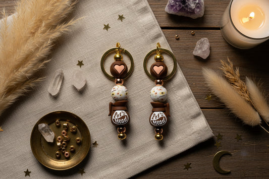 Keychains with heart and 'Pot Head' design on a gold stand against a gray background