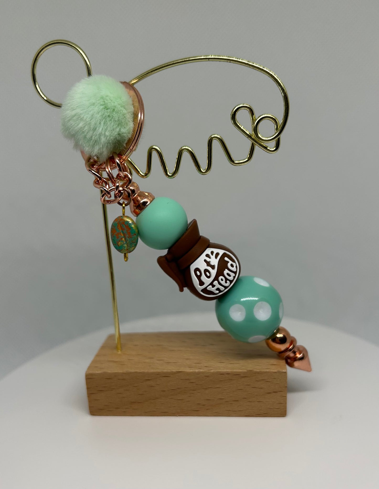 Decorative pot head keychain bag charm with beads on a wooden base against a white background