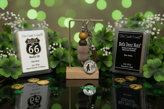 Decorative items including wax melts and a big foot keychain on a reflective surface with a green, bokeh background.