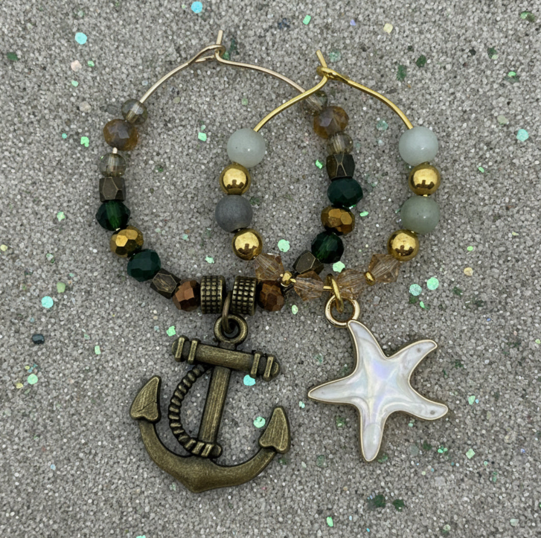 Wine glass charms with anchor and starfish charms on a textured surface. His and hers. 