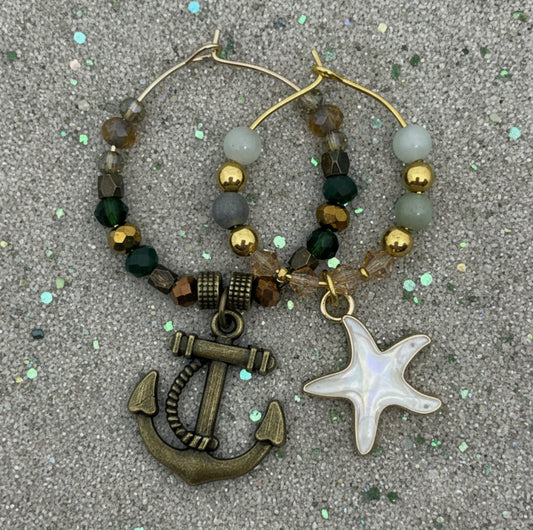Wine glass charms with anchor and starfish charms on a textured surface. His and hers. 