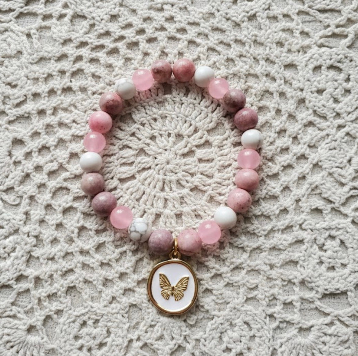 Beaded bracelet with a butterfly charm on a lace background