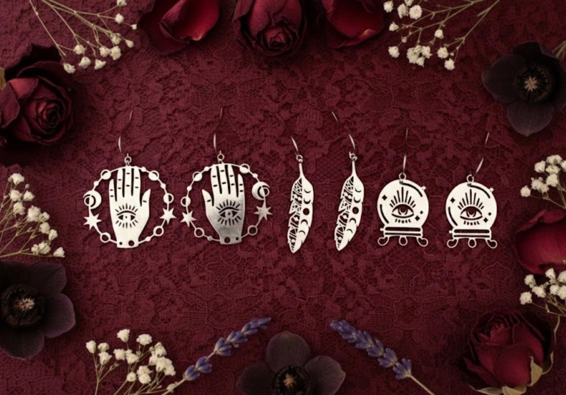 Set of stainless steel fortune teller mystical earrings on a dark red background with flowers