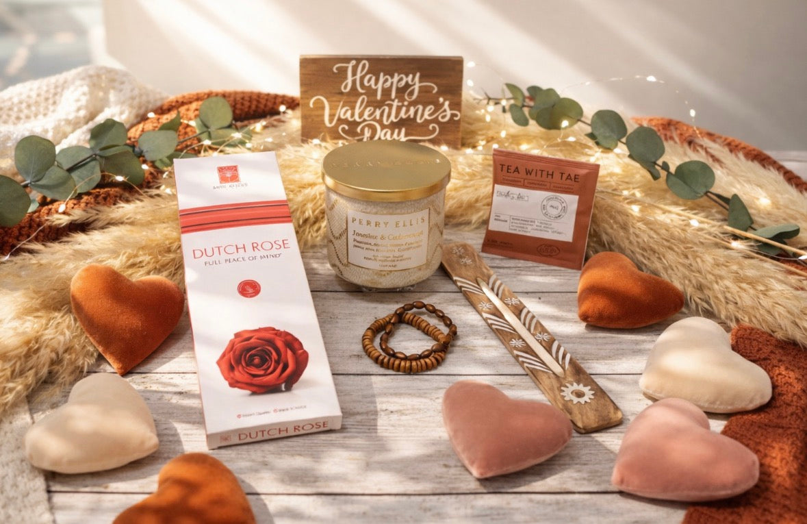 Valentine's Day-themed items including a candle, heart-shaped objects, and a box of Dutch Rose incense on a wooden surface.