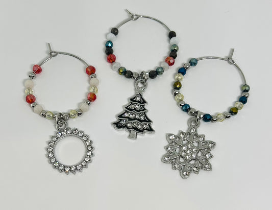 Set of three wine glass charms with Christmas-themed pendants on a white background. tree. snowflake. wreath. 