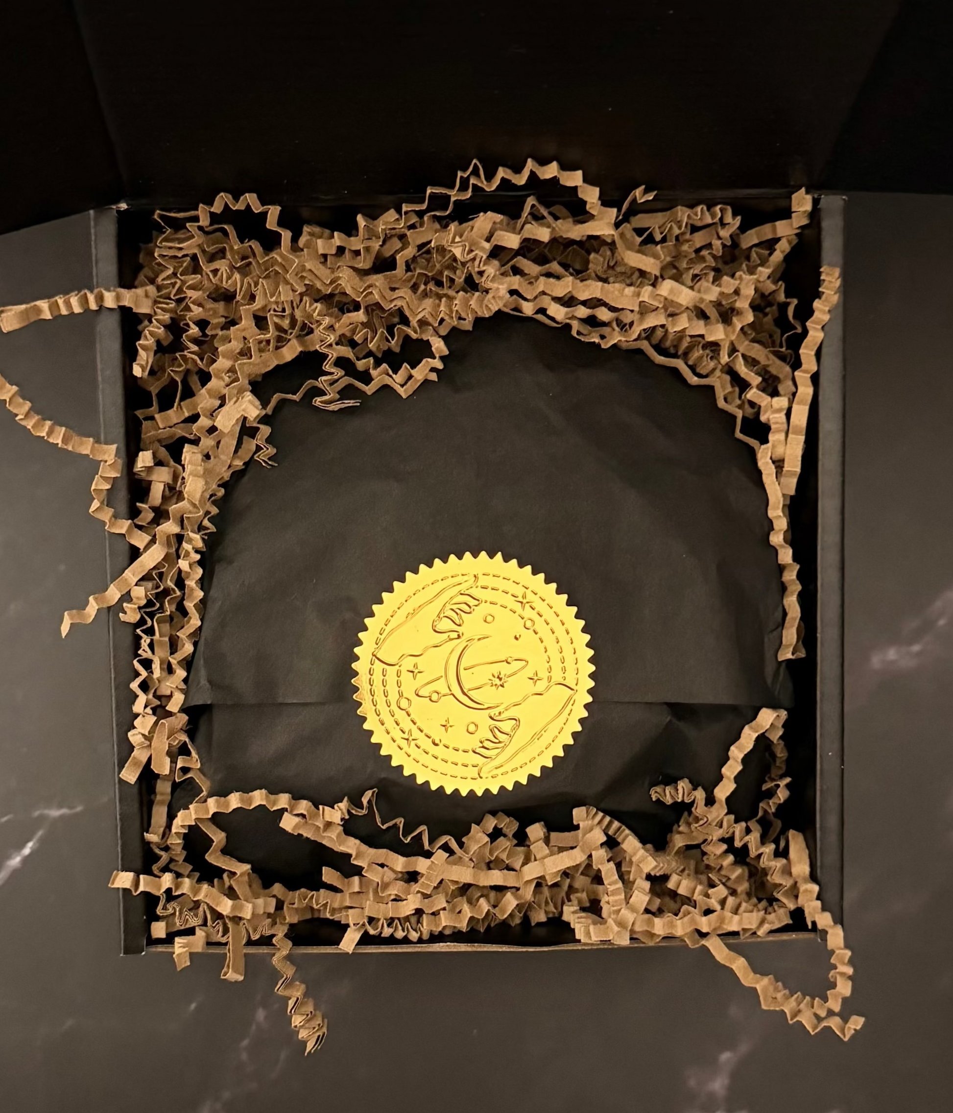 Gold label unisex fragrance gift set on a black surface with crinkled brown paper