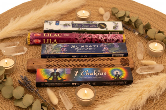 Incense sticks with various labels on a wooden tray surrounded by candles and crystals. Ethereal by Lez.