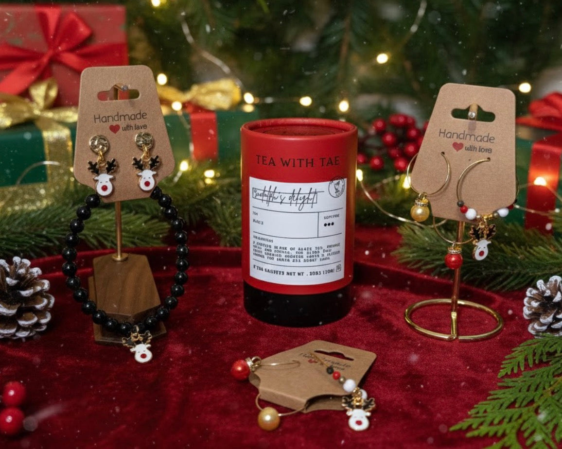 Rudolph Tea with Tae canister with festive earrings, onyx reindeer bracelet on stands against a festive background