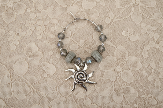 Silver sun charm with beads on a lace background