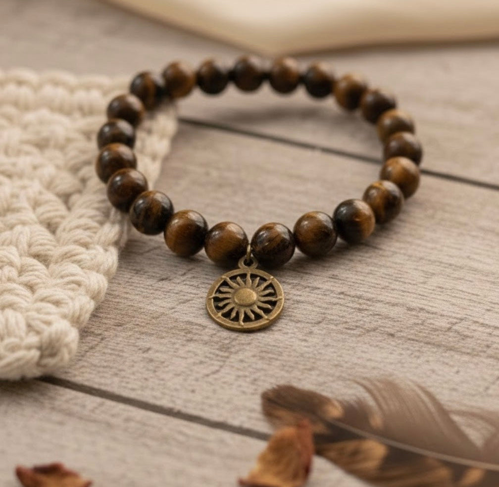 Tigers Eye beaded bracelet with a sun charm on a wooden surface