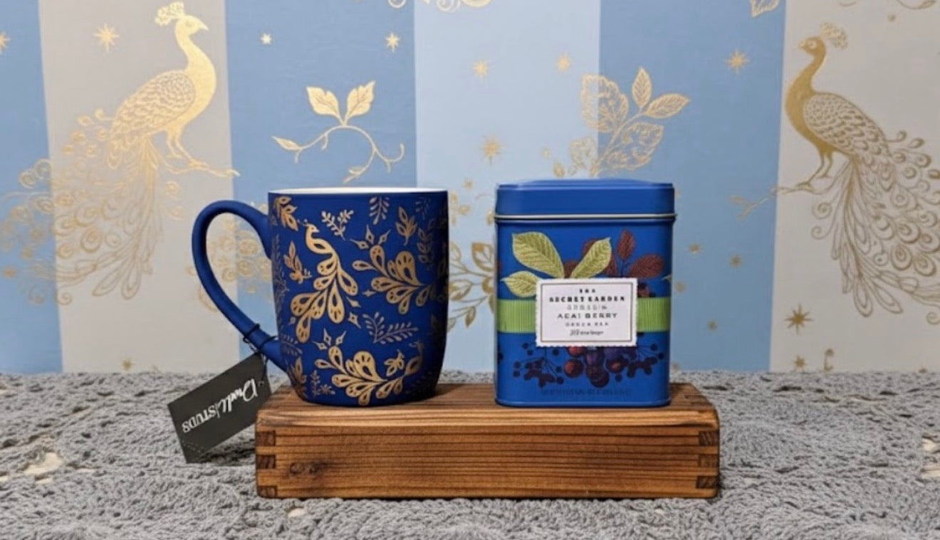Matte Blue and gold peacock mug and tea canister on a wooden stand with decorative background