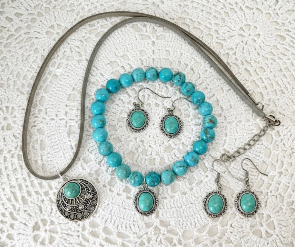 Turquoise beaded jewelry set with silver accents on a textured white surface