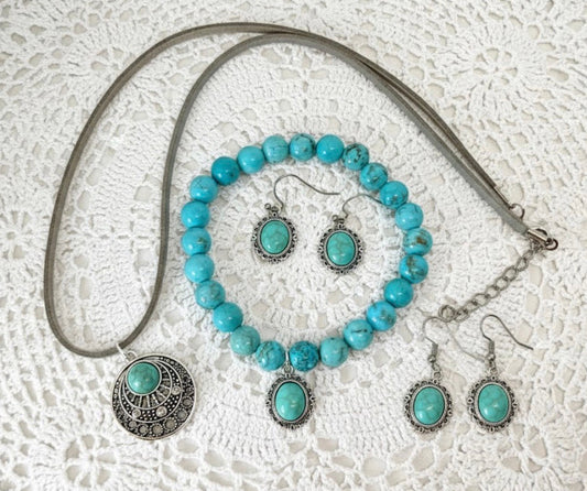 Turquoise beaded jewelry set with silver accents on a textured white surface