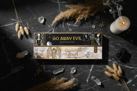 Product packaging labeled 'Go Away Evil Guardian Angel' on a dark surface with decorative elements.