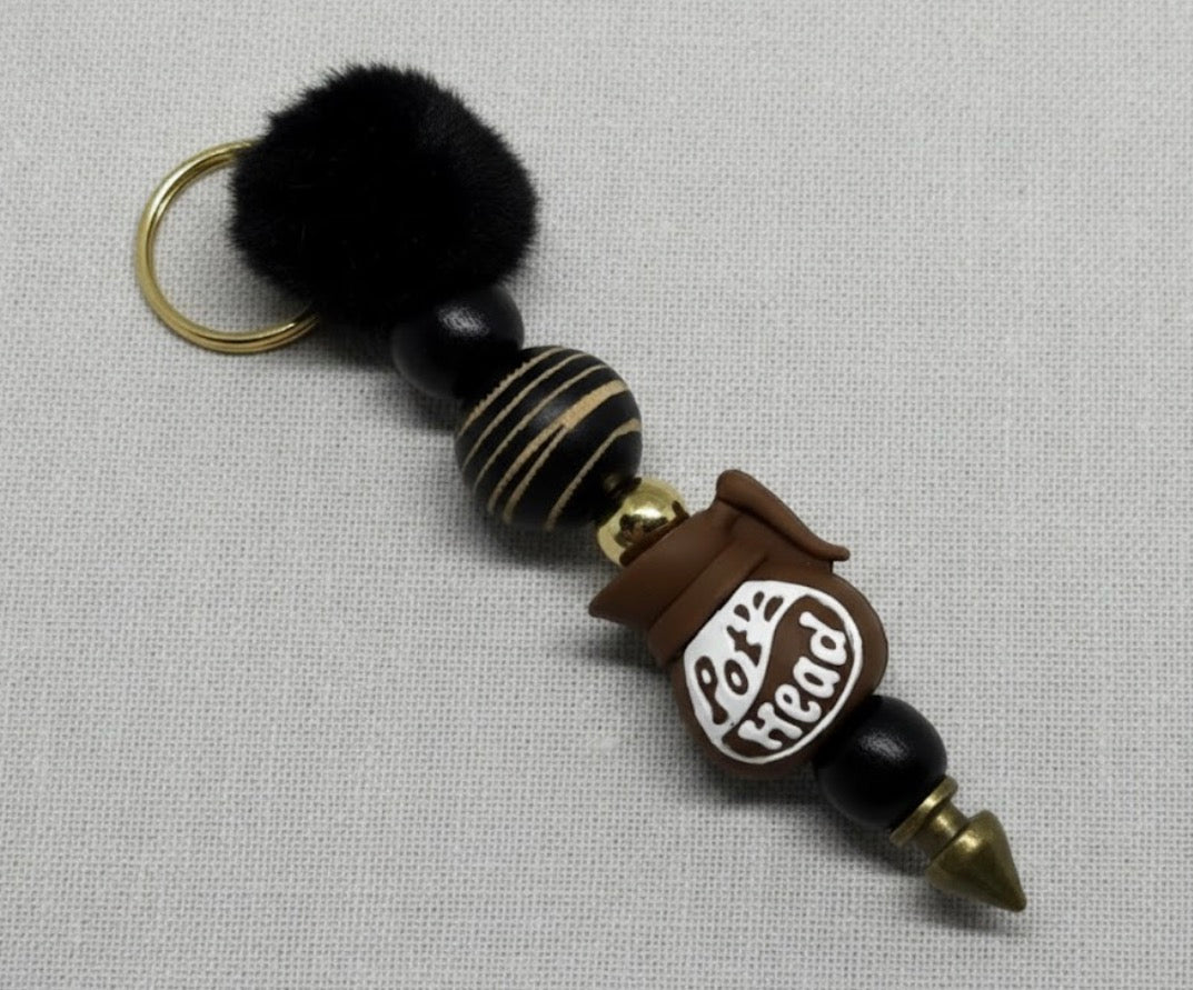 Pot Head Keychain with black pom-pom, wooden beads, on a gray background