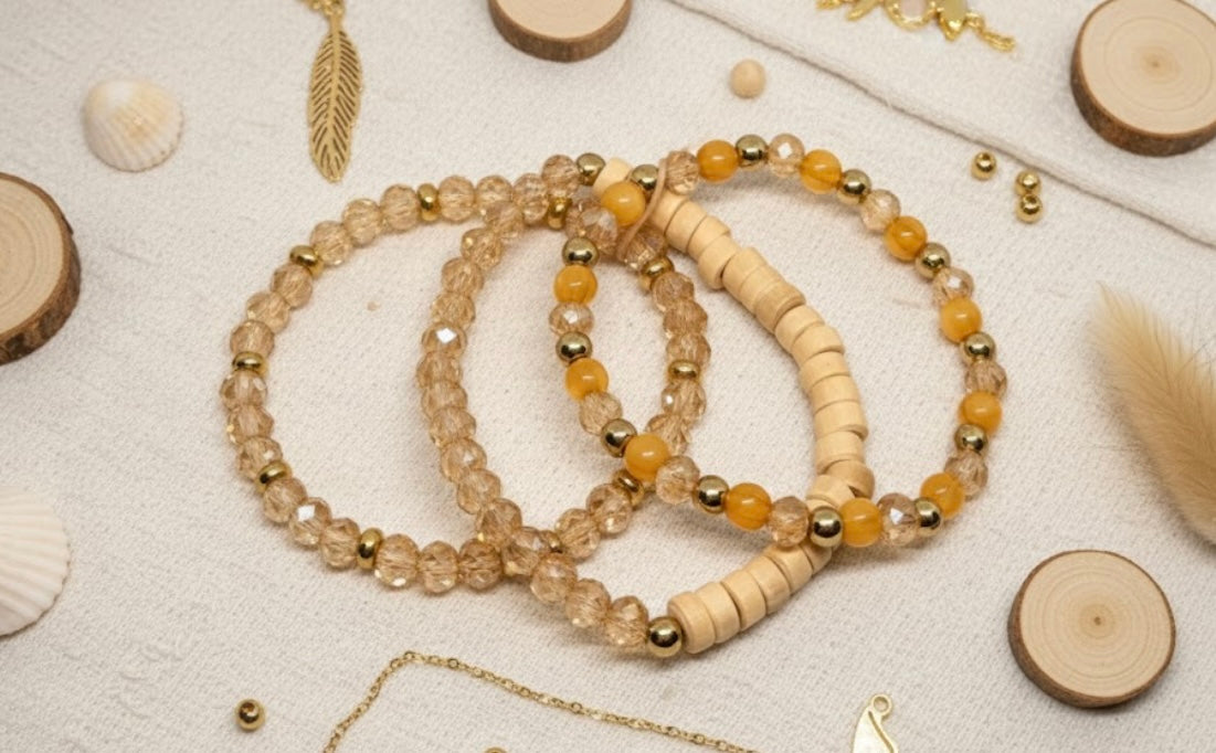 Three champagne glass colored beaded bracelets on a textured surface with natural elements.
