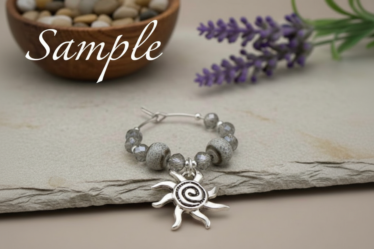 Drink Charm with sun charm on a stone surface with lavender and stones in the background.
