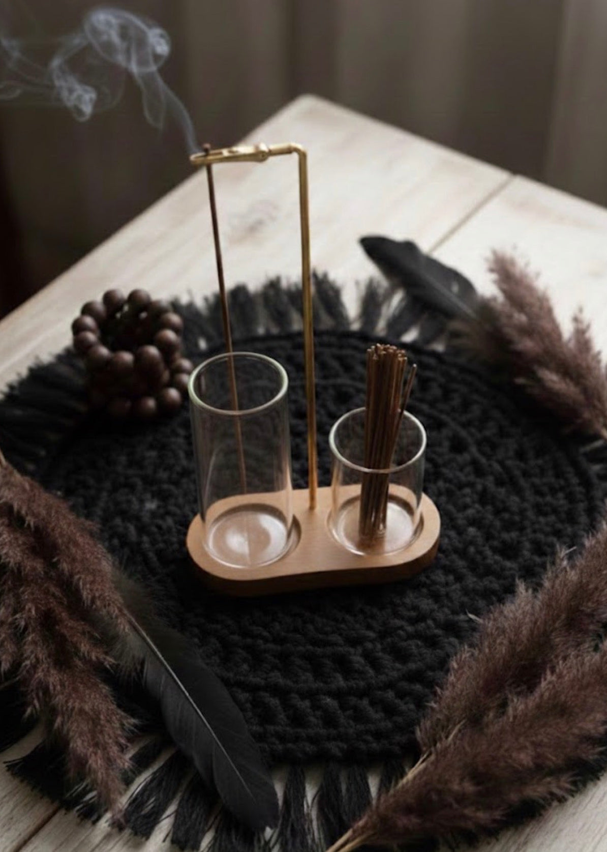Wooden and glass incense holder with glass cones on a textured surface with decorative elements.