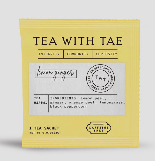Yellow lemon ginger tea sachet with 'Tea with Tae' branding on a light gray background