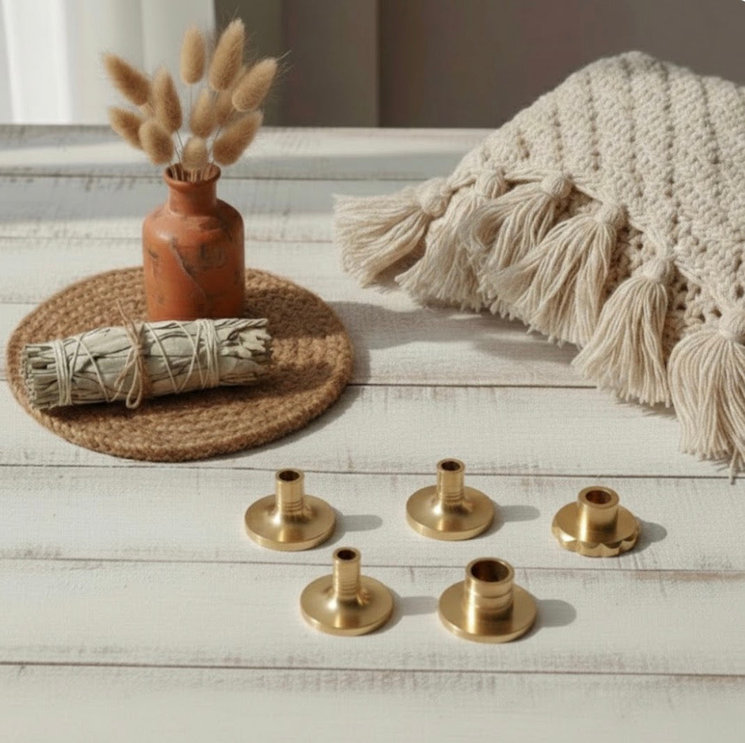 Set of brass incense holders on a wooden surface with decorative items including a vase with dried plants and a bundle of sage.