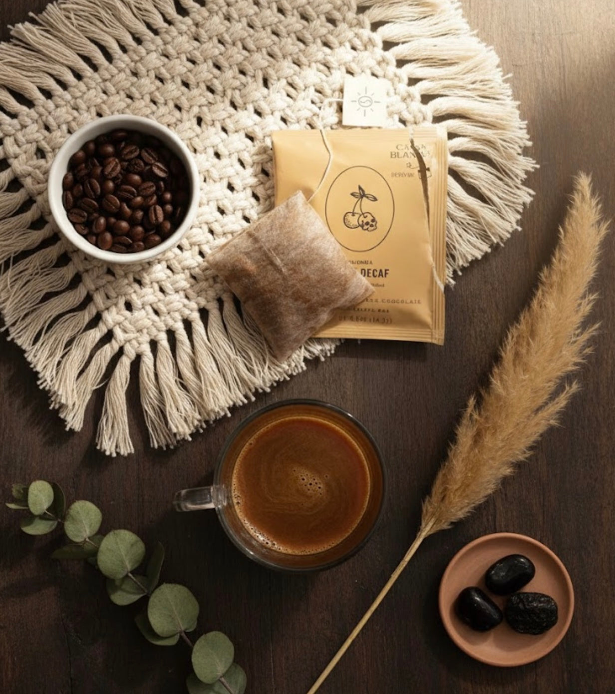 Coffee beans, a cup of coffee, a package of steeped coffee, and decorative elements on a textured surface.