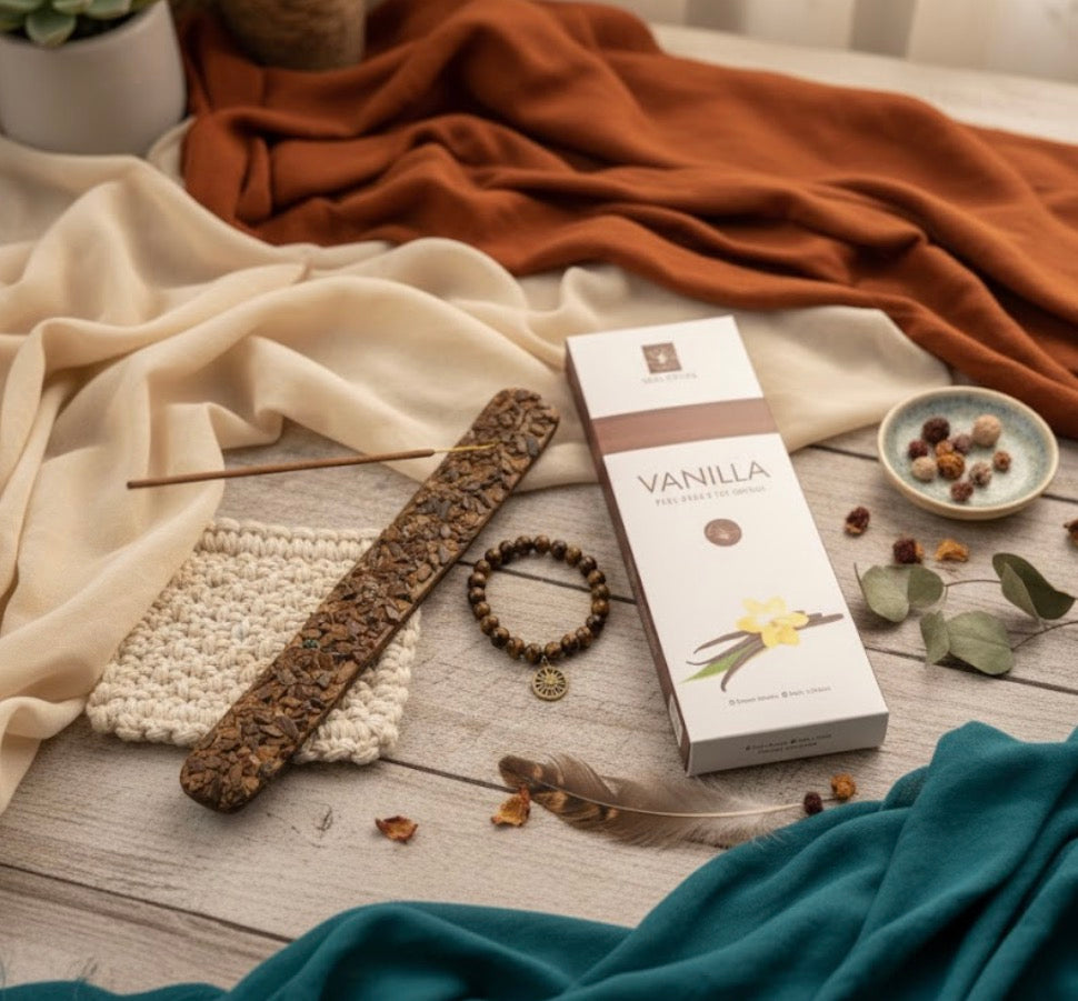 Vanilla incense packaging, incense holder, charm bracelet on a wooden surface with decorative items and fabrics.