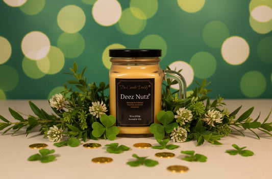 Jar of 'Deez Nutz' candle with decorative greenery and coins on a bokeh background