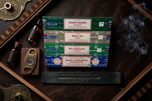 Set of Satya incense boxes on a dark wooden surface with smoke and decorative items. Ethereal by Lez. Nag Champa, Green Champa, Black Ice, 60’s Patchouli. 