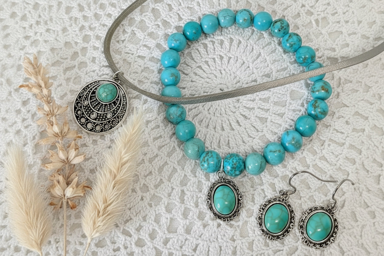 Turquoise beaded necklace with silver charms and earrings on a textured white surface