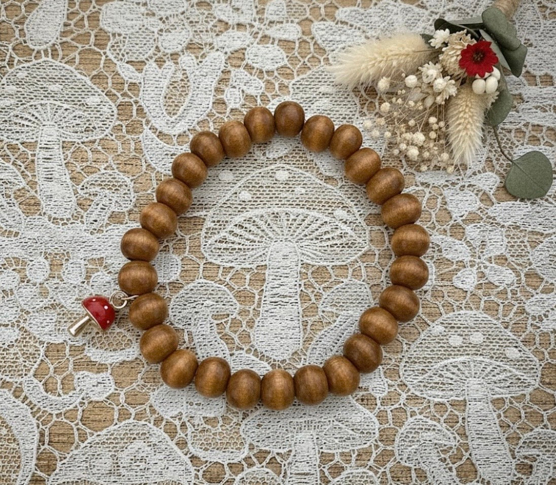 Wooden beaded bracelet with a red mushroom charm on a lace background
