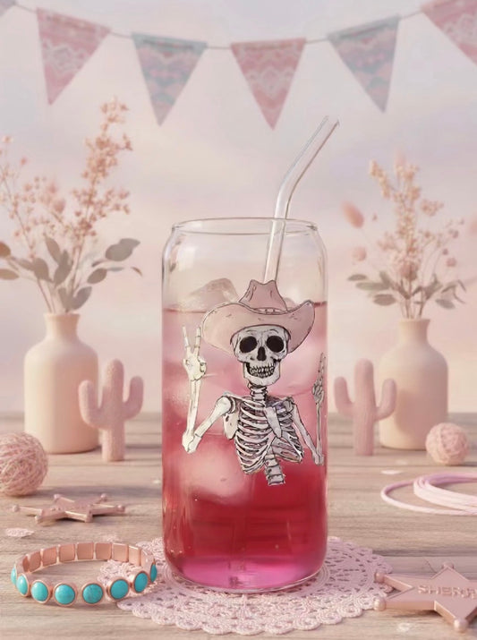 Can Glass with a skeleton design on a pink drink, surrounded by decorative items.