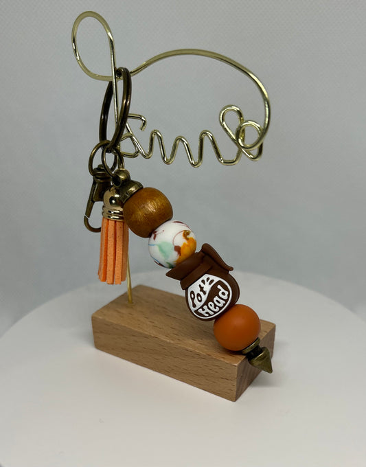 Decorative keychain with beads and a wooden base on a white background. Pot head bag charm. Pot head keychain. 